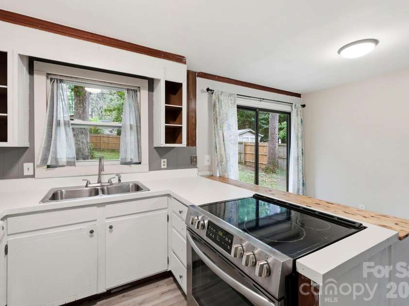 36 Medlin Lane, Flat Rock, NC 28731.  MLS# CAR4428597, YatesRealty ID 53594. Functional kitchen layout includes an electric range, peninsula workspace, and easy connection to the dining area.