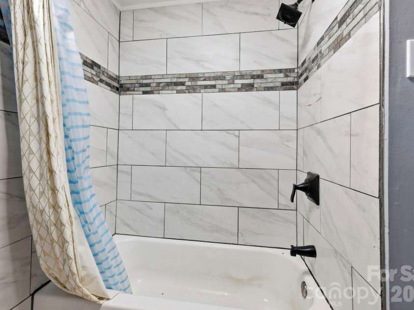 36 Medlin Lane, Flat Rock, NC 28731.  MLS# CAR4428597, YatesRealty ID 53594. Tub and shower surround features attractive tilework with a decorative accent.