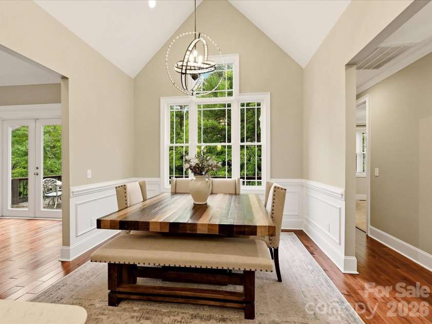 3167 James Plantation Drive, Denver, NC 28037.  MLS# CAR4429243, YatesRealty ID 53666. A light-filled breakfast/dining area features vaulted ceilings, hardwood floors, elegant wainscoting, a statement chandelier, and expansive windows overlooking the surrounding greenery.