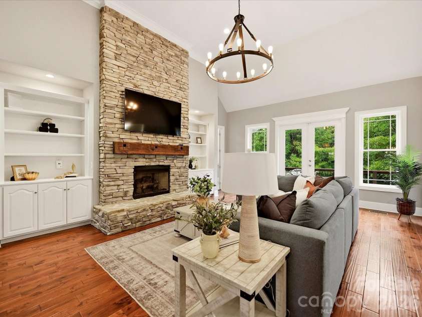 3167 James Plantation Drive, Denver, NC 28037.  MLS# CAR4429243, YatesRealty ID 53666. A spacious Great Room showcases a dramatic floor-to-ceiling stacked-stone fireplace with a rustic wood mantel, custom built-ins, vaulted ceilings, beautiful floors, and abundant natural light.