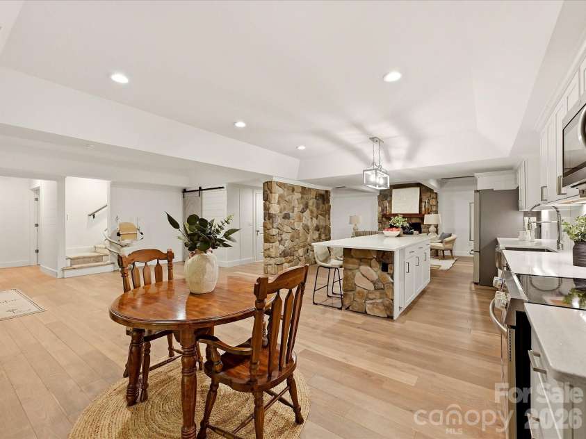 3167 James Plantation Drive, Denver, NC 28037.  MLS# CAR4429243, YatesRealty ID 53666. The finished basement level offers an open, versatile layout with a full kitchen, dining area, stone architectural accents, light wood flooring, and multiple spaces for relaxing or entertaining.