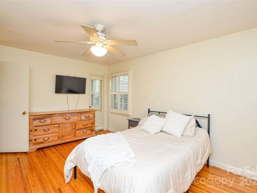 2429 Sugar Mill Road, Charlotte, NC 28210.  MLS# CAR4245721, YatesRealty ID 5405. Another view of the Primary Bedroom showing ceiling fan, warm hardwood flooring, and entrance to the full bath.
