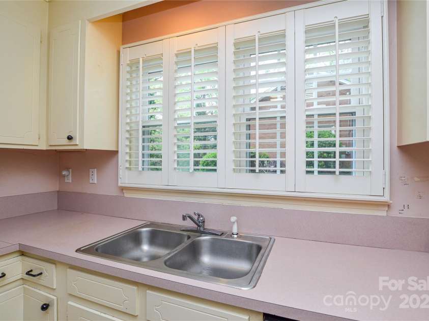 2429 Sugar Mill Road, Charlotte, NC 28210.  MLS# CAR4245721, YatesRealty ID 5405. Kitchen view showing windows with custom plantation shutters and classic solid wood cabinets.