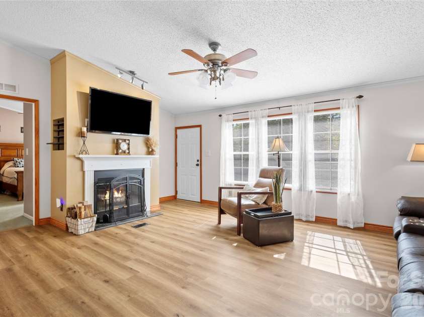 183 Gobbler Circle, Horse Shoe, NC 28742.  MLS# CAR4430660, YatesRealty ID 54240. Inviting living room with a fireplace, updated flooring, and crown molding.