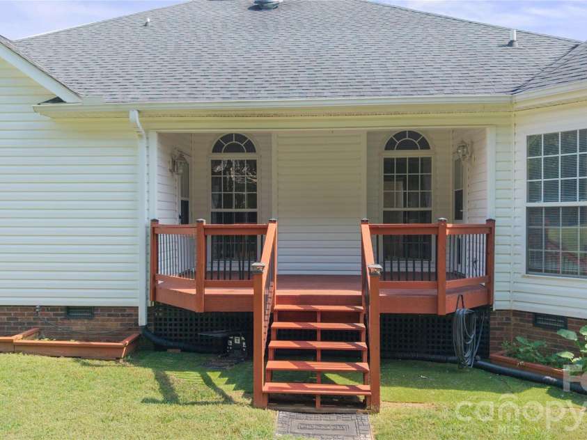 1011 Overhill Drive, Salisbury, NC 28144.  MLS# CAR4429292, YatesRealty ID 54283. Inviting covered back deck with stained wooden railings, centered steps down to the lawn, and direct access doors through to the kitchen on the right and primary suite on the left.