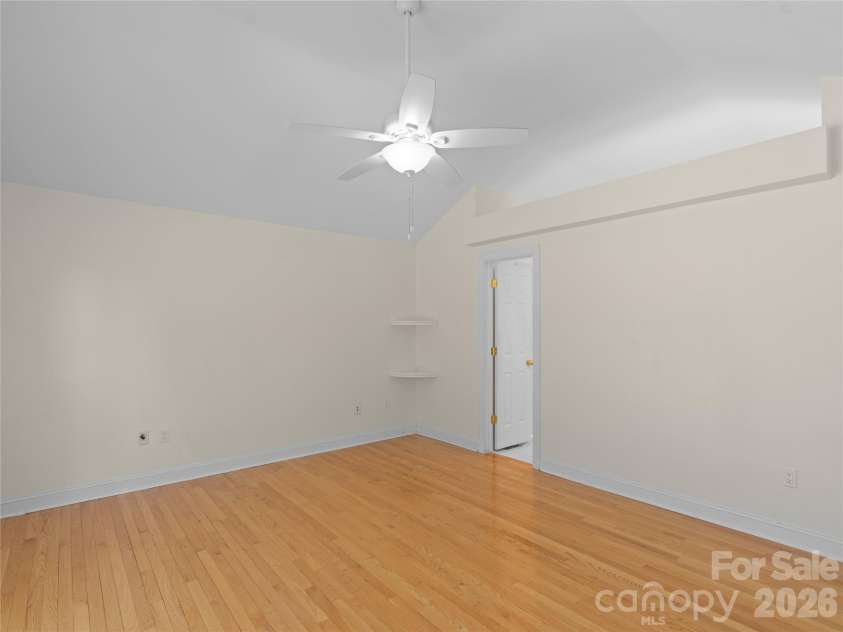 1011 Overhill Drive, Salisbury, NC 28144.  MLS# CAR4429292, YatesRealty ID 54283. Spacious primary suite featuring soaring vaulted ceilings, warm hardwood flooring, a modern ceiling fan, high display ledge or plant shelf and an open doorway leading seamlessly into the ensuite bath.