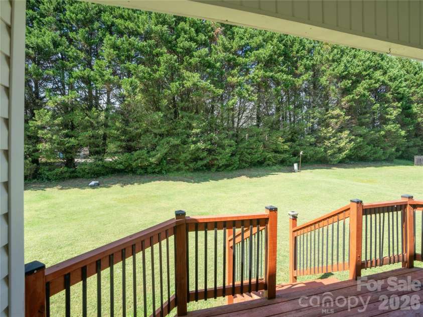 1011 Overhill Drive, Salisbury, NC 28144.  MLS# CAR4429292, YatesRealty ID 54283. View from the covered deck overlooking a flat, grassy backyard bordered by a dense line of mature evergreen trees for added privacy.