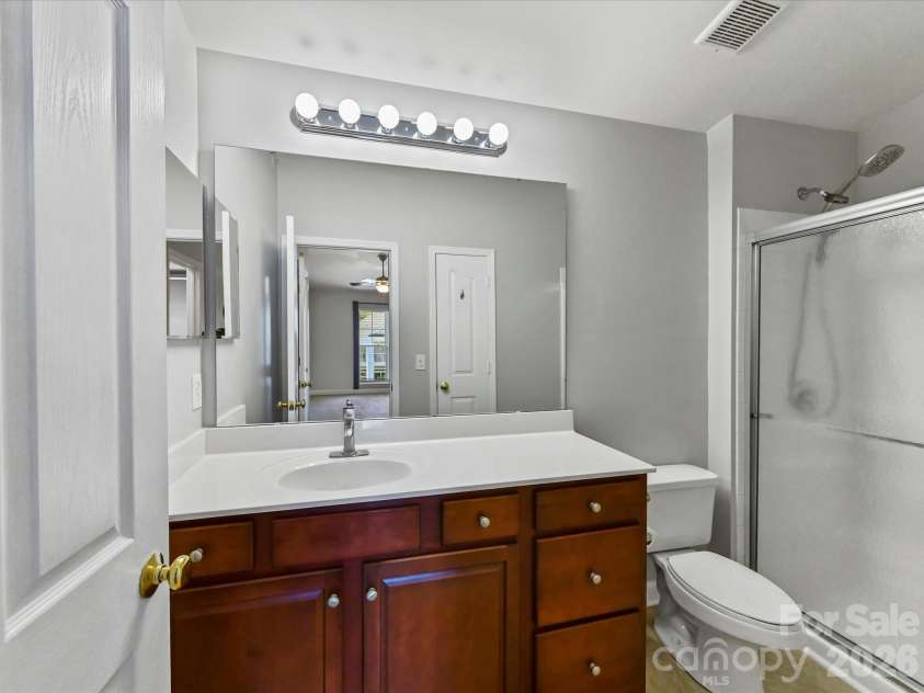 9031 Mcdowell Creek Court, Cornelius, NC 28031.  MLS# CAR4428404, YatesRealty ID 54302. Primary bath featuring a spacious vanity with ample storage, large mirror, and a tiled shower with sliding glass doors.