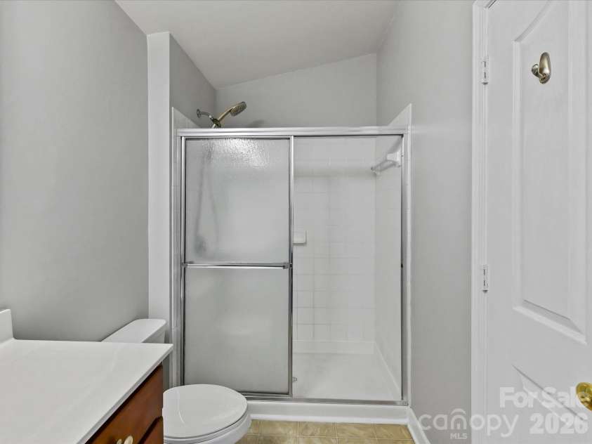 9031 Mcdowell Creek Court, Cornelius, NC 28031.  MLS# CAR4428404, YatesRealty ID 54302. Primary bath featuring a spacious vanity with ample storage, large mirror, and a tiled walk-in shower with sliding glass doors.