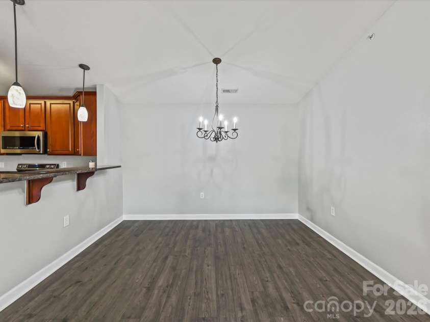 9031 Mcdowell Creek Court, Cornelius, NC 28031.  MLS# CAR4428404, YatesRealty ID 54302. Spacious dining area featuring LVP flooring, a vaulted ceiling, decorative chandelier, and a convenient breakfast bar connecting seamlessly to the kitchen.
