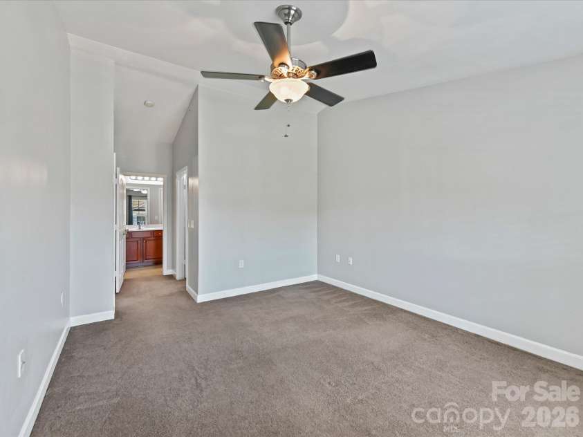 9031 Mcdowell Creek Court, Cornelius, NC 28031.  MLS# CAR4428404, YatesRealty ID 54302. Spacious primary suite featuring plush carpeting, a ceiling fan, and a large window providing abundant natural light and elevated community views.