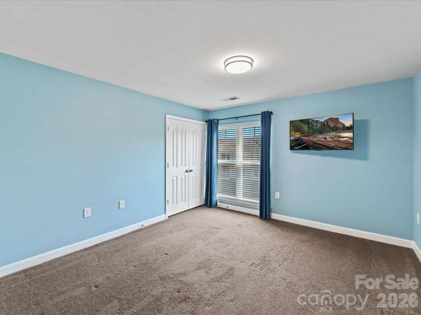 9031 Mcdowell Creek Court, Cornelius, NC 28031.  MLS# CAR4428404, YatesRealty ID 54302. Spacious second bedroom featuring plush carpeting, ample natural light, generous closet space, and flexible room for guests, a home office, or additional living space.