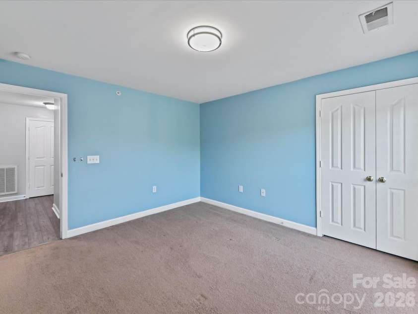 9031 Mcdowell Creek Court, Cornelius, NC 28031.  MLS# CAR4428404, YatesRealty ID 54302. Spacious second bedroom featuring plush carpeting, ample natural light, generous closet space, and flexible room for guests, a home office, or additional living space.