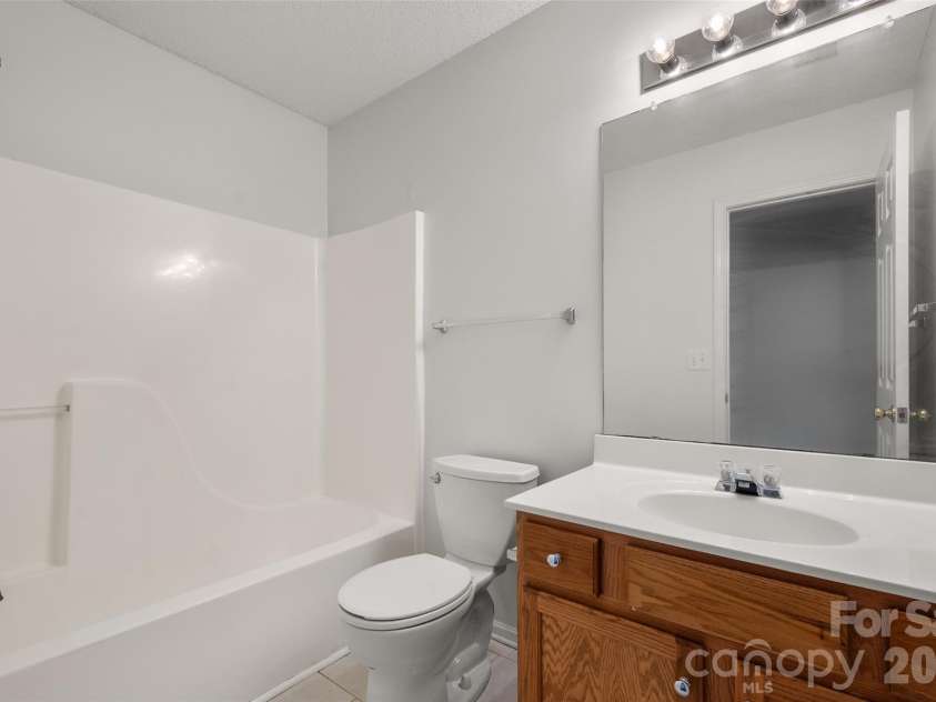 2738 Mill Valley Court, Matthews, NC 28105.  MLS# CAR4424420, YatesRealty ID 54340. Full upper-level guest bathroom featuring a tub/shower combination, spacious vanity with storage cabinetry, bright overhead vanity lighting, and crisp neutral finishes.