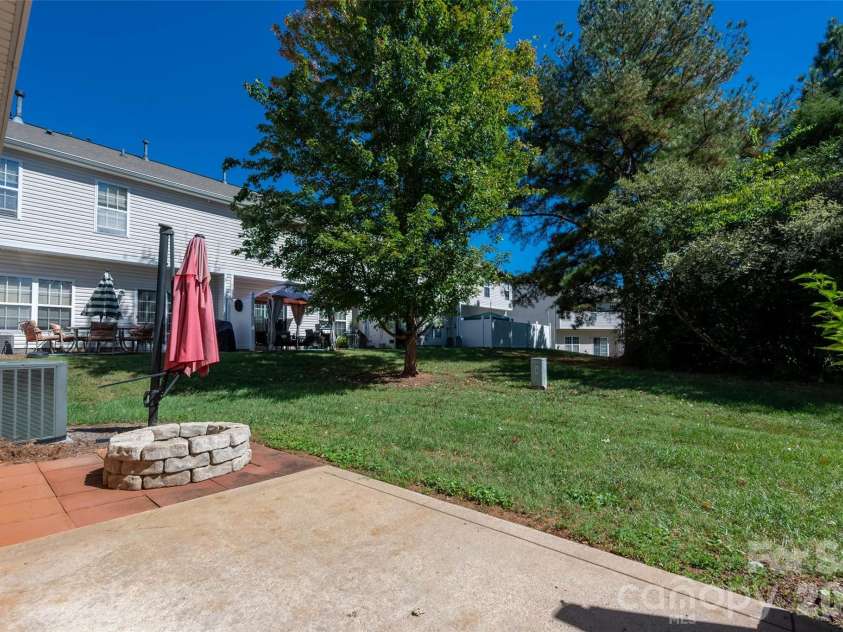 2738 Mill Valley Court, Matthews, NC 28105.  MLS# CAR4424420, YatesRealty ID 54340. Level backyard space surrounded by mature greenery and tree line view, ideal for outdoor relaxation, grilling, and entertaining guests.