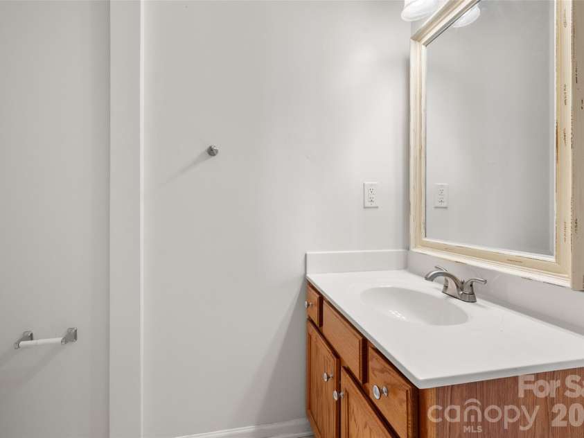 2738 Mill Valley Court, Matthews, NC 28105.  MLS# CAR4424420, YatesRealty ID 54340. Main-level half bath offering convenient access for guests, featuring a stylish vanity with ample counter space, clean neutral finishes, and framed mirror.