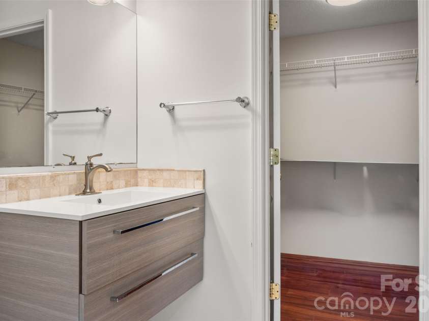 2738 Mill Valley Court, Matthews, NC 28105.  MLS# CAR4424420, YatesRealty ID 54340. Modern floating vanity with stone-look countertop and sleek hardware, located adjacent to a spacious walk-in closet with built-in wire shelving.