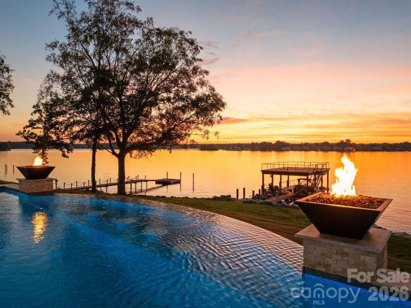 112 Birdsong Lane, Mooresville, NC 28117.  MLS# CAR4430430, YatesRealty ID 54482. Infinity-edge pool with fire bowls framed by a stunning Lake Norman sunset.