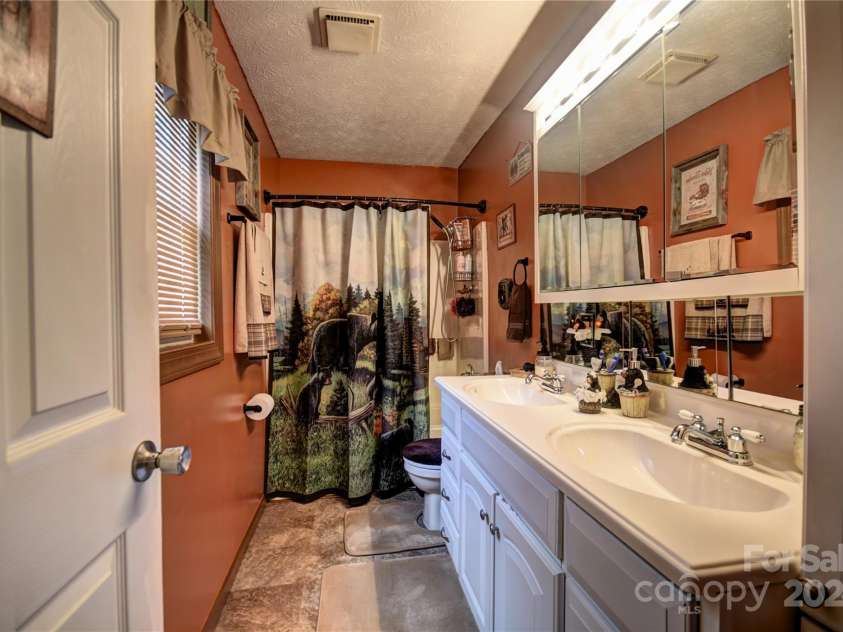 201 Acorn Lane, Clyde, NC 28721.  MLS# CAR4153632, YatesRealty ID 5499. En Suite Bath with dual vanity sinks and a tub/shower combo off the Primary BR