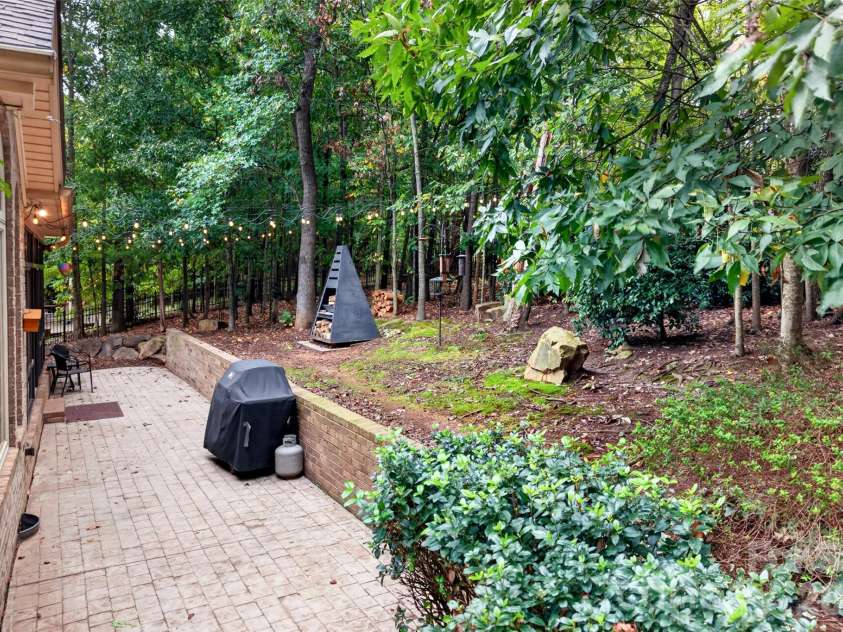 3941 Grovesner Street, Harrisburg, NC 28075.  MLS# CAR4423341, YatesRealty ID 55411. Wooded backyard with firepit that conveys and string lighting.