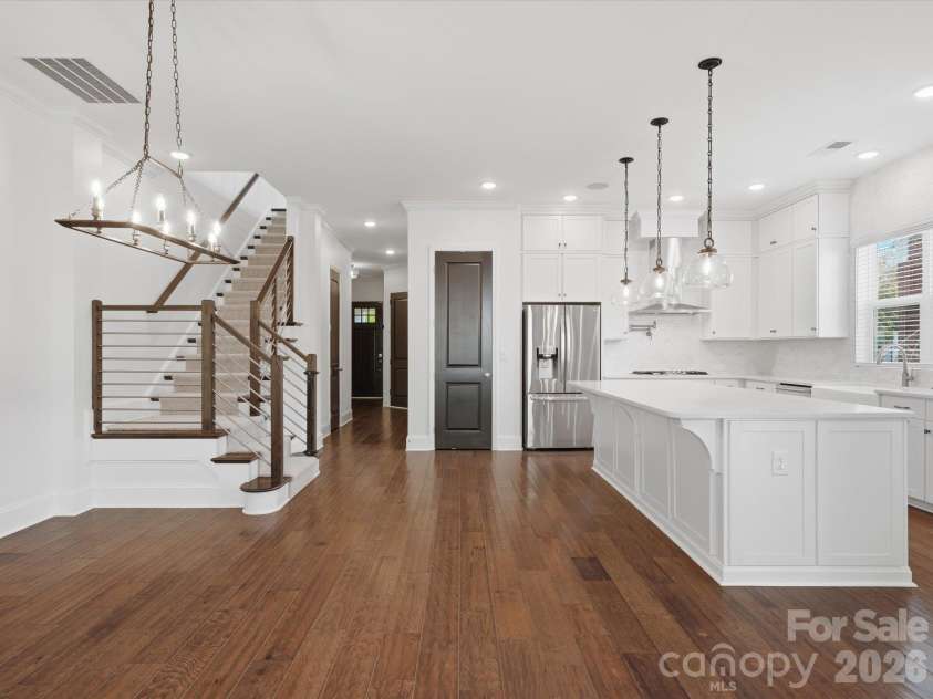 337 Belton Street, Charlotte, NC 28209.  MLS# CAR4431840, YatesRealty ID 55676. Open floor plan connecting the dining area, white chef's kitchen with oversized island, and modern staircase with horizontal metal railing. Ideal layout for entertaining.