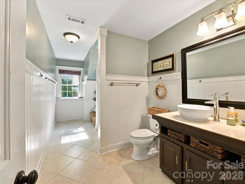 10709 Danesway Lane, Cornelius, NC 28031.  MLS# CAR4431451, YatesRealty ID 55685. The beautifully appointed Full Bath features a stylish vanity with vessel sink, classic wainscoting, tiled flooring, a glass-enclosed tiled shower, and convenient built-in shelving for ample storage.