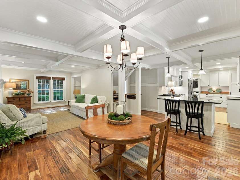 10709 Danesway Lane, Cornelius, NC 28031.  MLS# CAR4431451, YatesRealty ID 55685. The inviting dining area features rich hardwood floors, elegant coffered ceilings, a stylish chandelier, and sliding glass doors leading to the screened-in porch, creating a seamless flow for indoor-outdoor entertainin