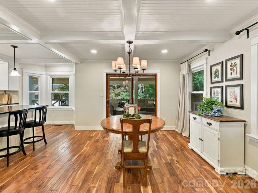 10709 Danesway Lane, Cornelius, NC 28031.  MLS# CAR4431451, YatesRealty ID 55685. The inviting dining area features rich hardwood floors, elegant coffered ceilings, a stylish chandelier, and sliding glass doors leading to the screened-in porch, creating a seamless flow for indoor-outdoor entertainin