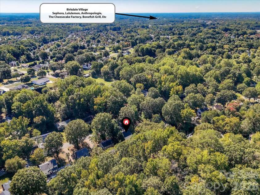 10709 Danesway Lane, Cornelius, NC 28031.  MLS# CAR4431451, YatesRealty ID 55685. This aerial view highlights the home's peaceful, tree-lined setting and convenient proximity to Birkdale Village, a premier shopping, dining, and entertainment destination featuring popular retailers, restaurants, and 