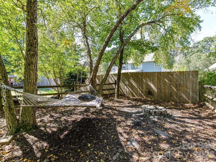 17127 Windy Oaks Court, Cornelius, NC 28031.  MLS# CAR4432499, YatesRealty ID 55826. This spacious, private backyard offers a peaceful tree-lined setting with mature landscaping, a charming hammock and fire pit area, a generous lawn, and a convenient detached storage building, perfect for outdoor re