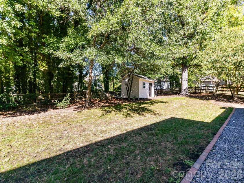 17127 Windy Oaks Court, Cornelius, NC 28031.  MLS# CAR4432499, YatesRealty ID 55826. This spacious, private backyard offers a peaceful tree-lined setting with mature landscaping, a charming hammock and fire pit area, a generous lawn, and a convenient detached storage building, perfect for outdoor re
