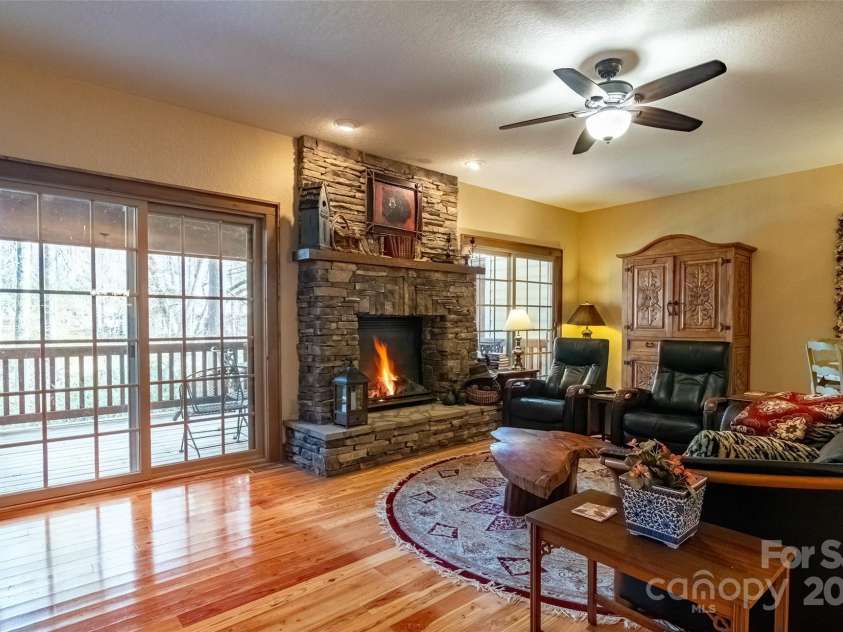 620 Sapphire Valley Road, Cashiers, NC 28717.  MLS# CAR4329121, YatesRealty ID 598. Living Room with its gorgeous hardwood floors, field stone fireplace, and open spaces. The sliders take you out to the rear covered wooden deck. All Living Room and Deck furniture conveys.