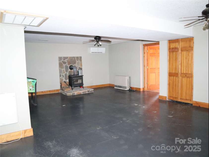 672/715 Windswept Ridge Road, Canton, NC 28716.  MLS# CAR4229345, YatesRealty ID 6077. House #1 - Family Room in basement with wood stove.