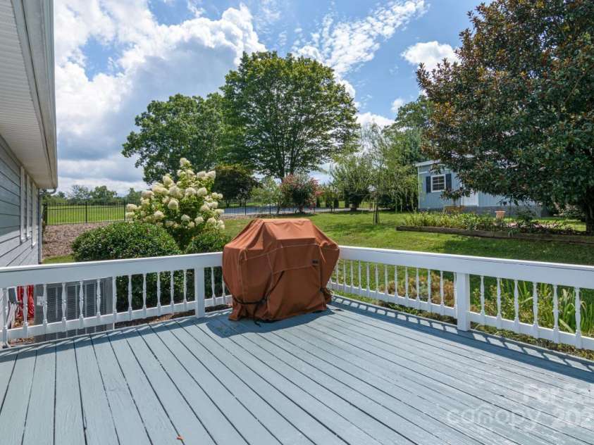 231 Kimberly Ann Drive, Hendersonville, NC 28792.  MLS# CAR4285461, YatesRealty ID 6092. Deck overlooks back yard fully encircled by metal fencing. Outbuilding (12x24, installed 2025) at right) has electricity and ramp access.