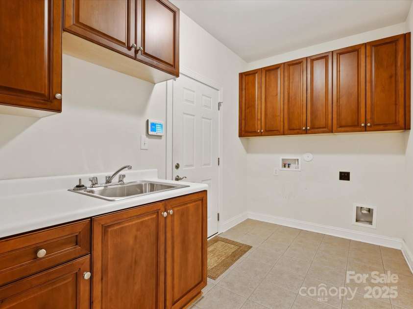 1910 Mezzo Court, Matthews, NC 28105.  MLS# CAR4245911, YatesRealty ID 6115. Large laundry room with sink, cabinets and door to the garage