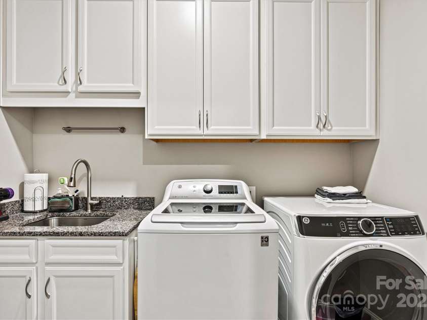 8718 Festival Way, Charlotte, NC 28215.  MLS# CAR4243722, YatesRealty ID 6122. Conveniently located separate laundry room features abundant storage with overhead cabinetry, plus lower cabinet with built-in sink and granite counters for practical functionality.