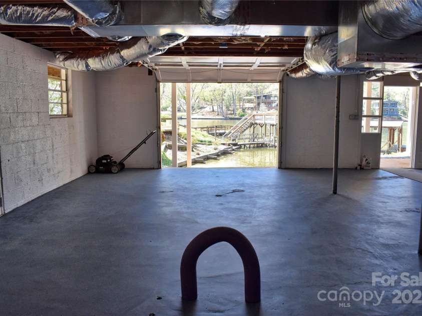 458 Pinehaven Drive, Badin Lake, NC 28127.  MLS# CAR4242649, YatesRealty ID 6402. Basement area currently serves as a covered boat/jet ski storage with a paved boat ramp into the lake.