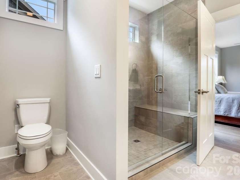 19 Craftsman Overlook Ridge, Arden, NC 28704.  MLS# CAR4342379, YatesRealty ID 6451. Primary tiled shower with bench seat, window, low profile entry.