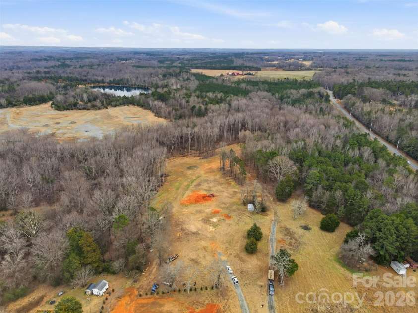 9729-B Flowes Store Road, Midland, NC 28107.  MLS# CAR4345762, YatesRealty ID 6658. Aerial view of the lot - home will be positioned near the orange dirt in the center, or possibly behind it, closer to woods. Will have a paved driveway leading to the house.