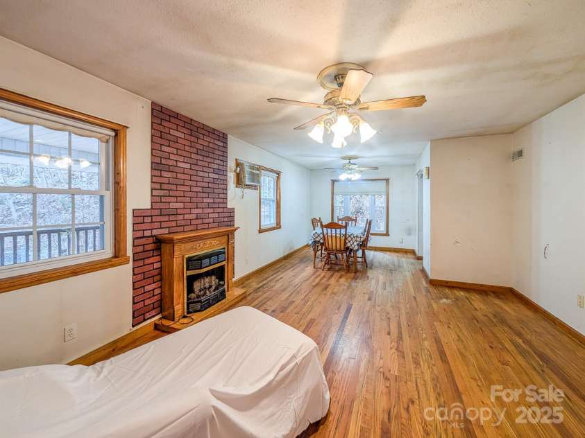 77 Griffith Branch Road, Green Mountain, NC 28740.  MLS# CAR4328405, YatesRealty ID 668. Spacious living area features hardwood flooring, propane gas log fireplace and access to covered wrap-around porch. Could use for small dining area as shown. 