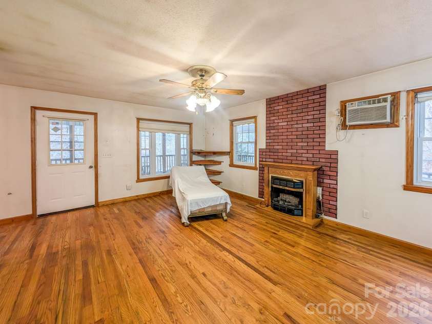 77 Griffith Branch Road, Green Mountain, NC 28740.  MLS# CAR4328405, YatesRealty ID 668. Spacious living area features hardwood flooring, propane gas log fireplace and access to covered wrap-around porch. 