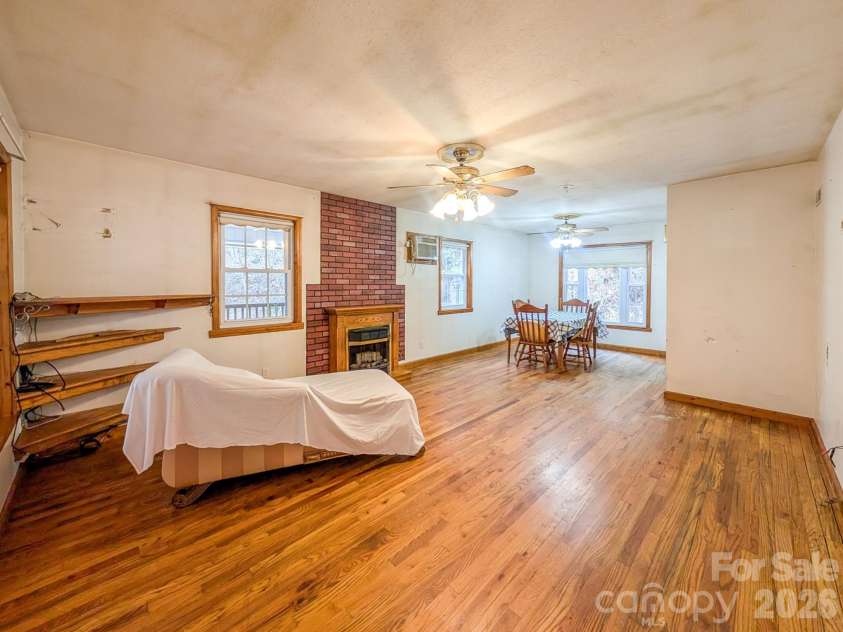 77 Griffith Branch Road, Green Mountain, NC 28740.  MLS# CAR4328405, YatesRealty ID 668. Spacious living area features hardwood flooring, propane gas log fireplace and access to covered wrap-around porch. Could use space for small dining area as shown. 