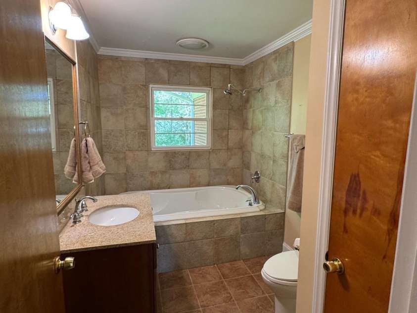 5119 Beckford Drive, Charlotte, NC 28226.  MLS# CAR4247630, YatesRealty ID 6706. The hall bathroom features an updated tile floor and walls, a Jacuzzi tub/shower combination, a newer toilet, and a convenient linen closet for extra storage.