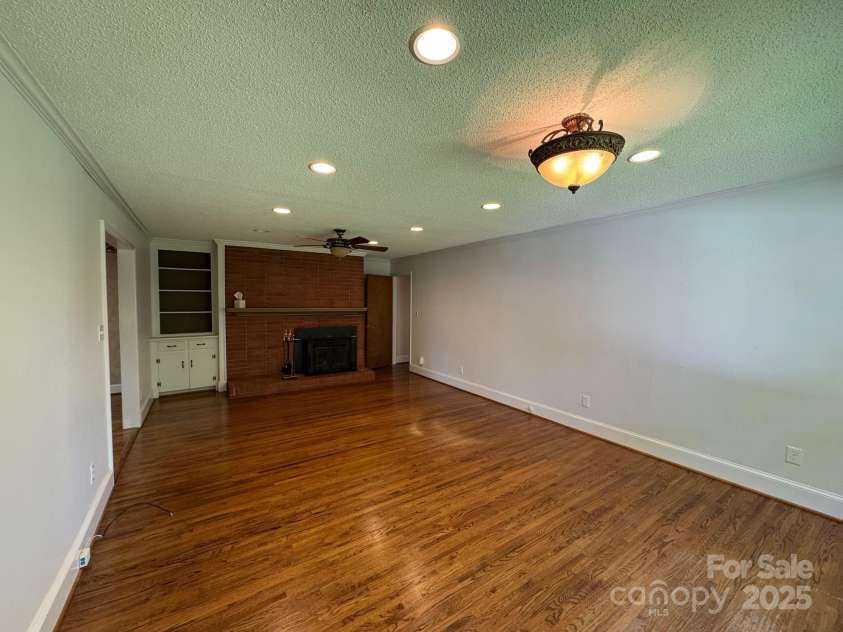 5119 Beckford Drive, Charlotte, NC 28226.  MLS# CAR4247630, YatesRealty ID 6706. Warm and inviting, the den offers beautiful hardwood floors, custom built-in shelving, a striking full brick chimney, and easy access to the kitchen — perfect for relaxed living and entertaining.