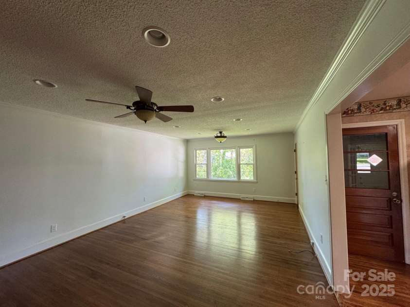 5119 Beckford Drive, Charlotte, NC 28226.  MLS# CAR4247630, YatesRealty ID 6706. Warm and inviting, the den offers beautiful hardwood floors, custom built-in shelving, a striking full brick chimney, and easy access to the kitchen — perfect for relaxed living and entertaining.