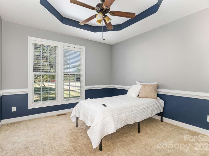9404 Perimeter Court, Zebulon, NC 27597.  MLS# CAR4191333, YatesRealty ID 6842. Bedroom 2 boasts an elegant tray ceiling, abundant natural light, and a stylish chair rail complemented by two-tone paint, adding a touch of sophistication to the space.