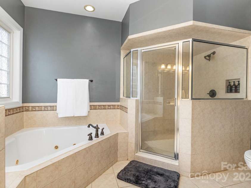 9404 Perimeter Court, Zebulon, NC 27597.  MLS# CAR4191333, YatesRealty ID 6842. The ensuite bathroom boasts a spacious jacuzzi tub and an expansive fully tiled walk-in shower, perfect for unwinding.