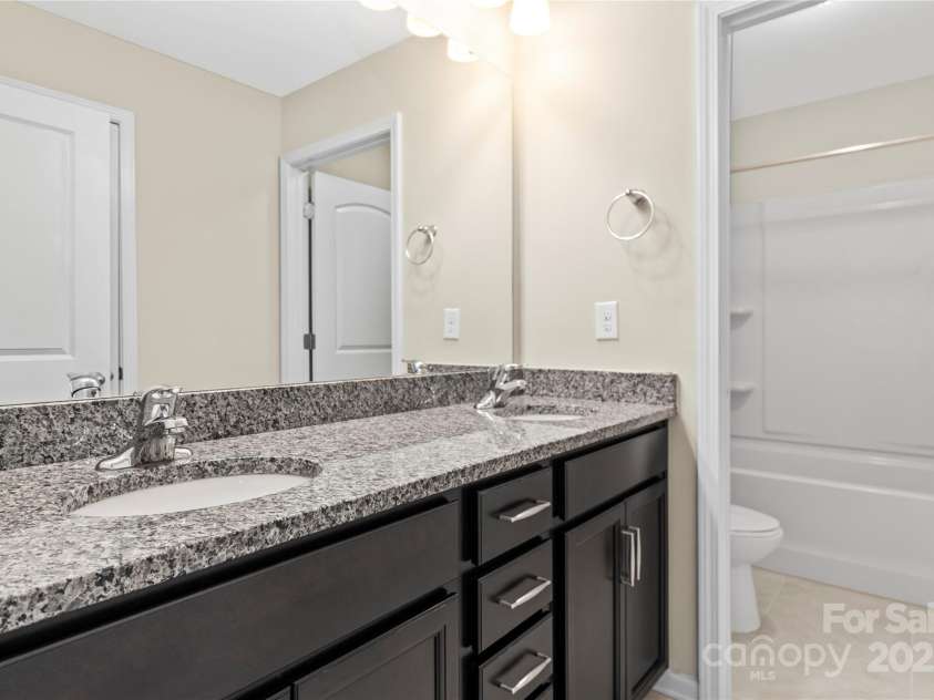 3023 Spinner Court, Denver, NC 28037.  MLS# CAR4142435, YatesRealty ID 6943. Bathroom #3 features dual vanity sinks with sleek granite countertops, offering both style and functionality for daily routines.