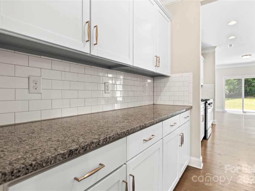 3023 Spinner Court, Denver, NC 28037.  MLS# CAR4142435, YatesRealty ID 6943. The butler's pantry stands as a sleek and organized extension of the kitchen, featuring ample storage shelves neatly arranged with glassware, dishes, and culinary essentials. The countertop gleams with polished surfaces, pe