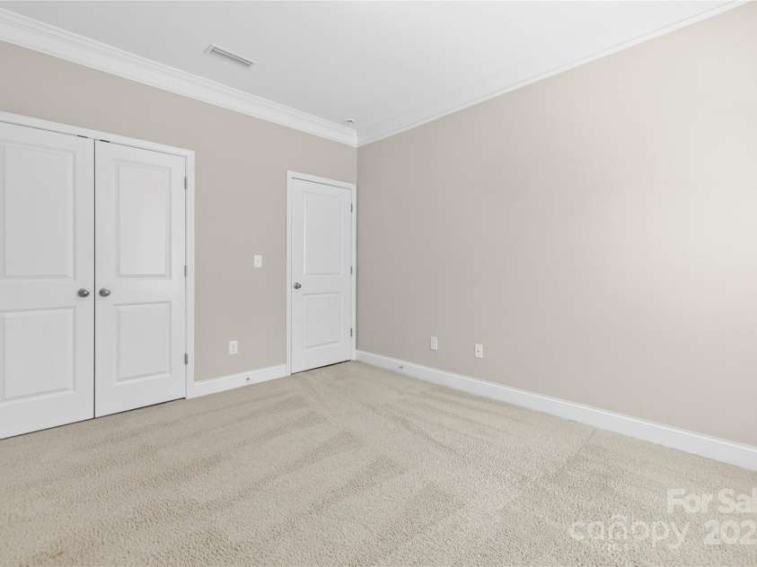 3023 Spinner Court, Denver, NC 28037.  MLS# CAR4142435, YatesRealty ID 6943. The guest bedroom on the main floor features a convenient closet, providing ample storage space and easy access for visitors' belongings.